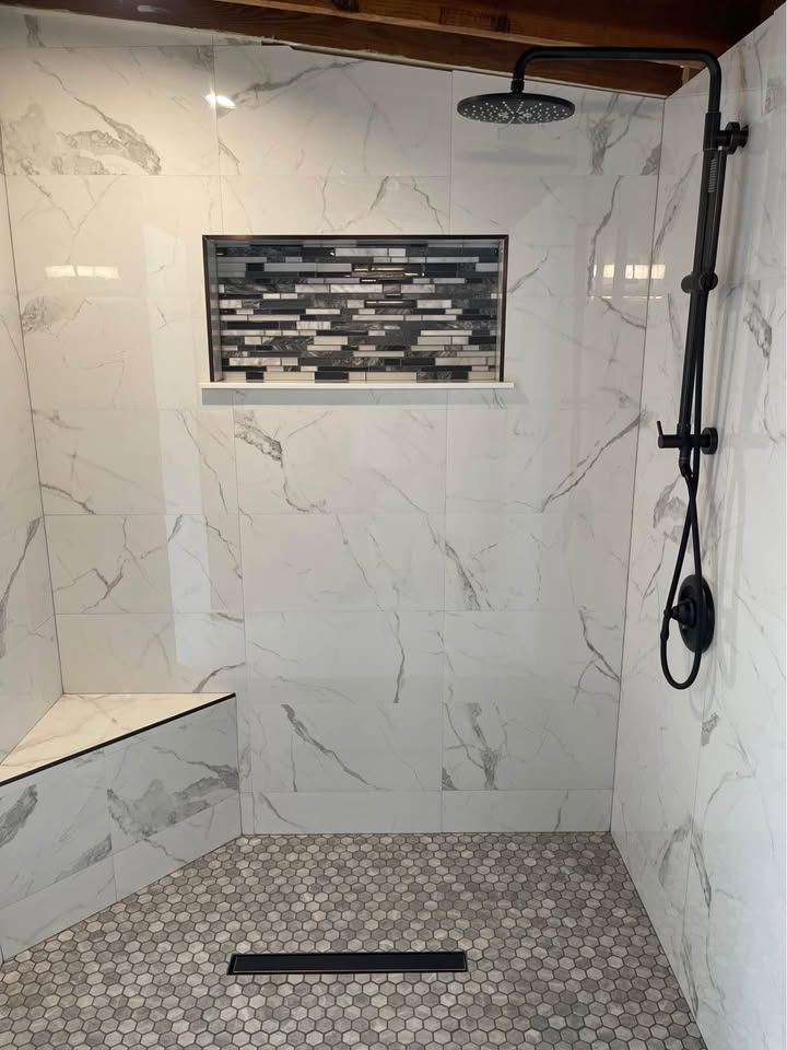 Walk-in shower fitted in place of an old bathtub, with tiled walls and a glass door