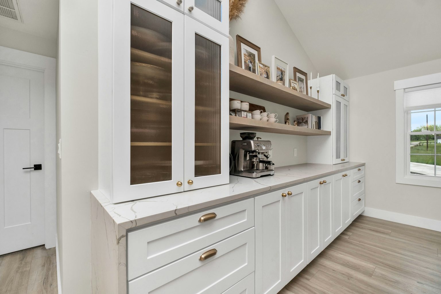 Custom butler pantry with white shaker cabinetry, quartz counter, fluted glass doors and brass hardware