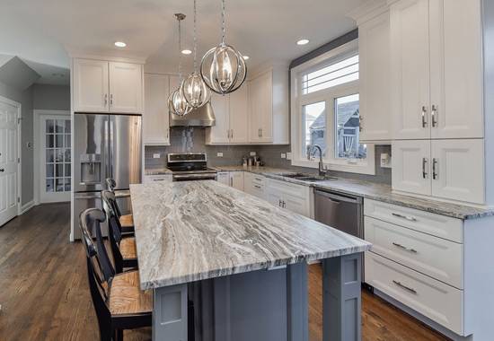 Remodeled kitchen with white shaker cabinetry, stone counters and stainless appliances