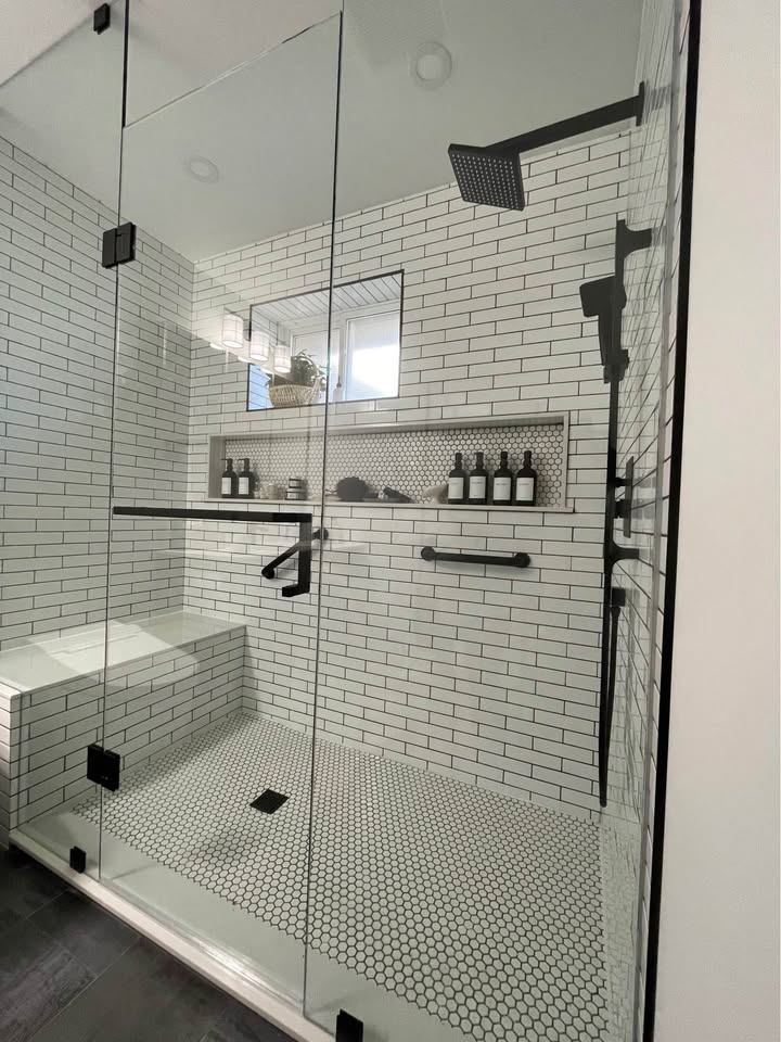 Walk-in shower with tiled walls, a glass enclosure and a built-in bench seat